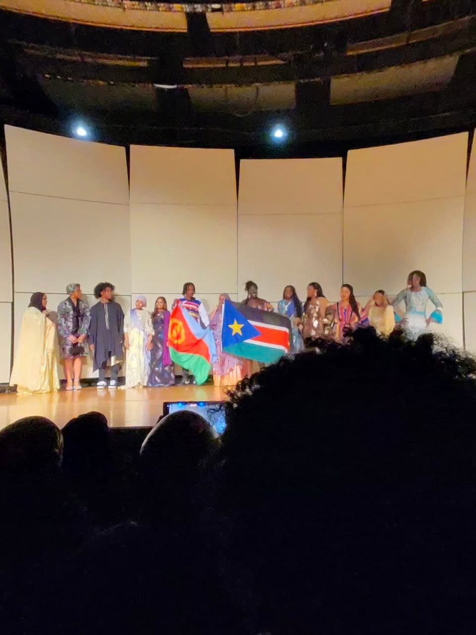 Students holding Eritrean and South Sudanese flags on stage during A Night in Africa